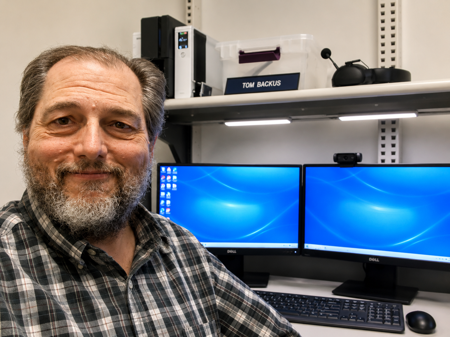 Tom Backus smiling at his workstation with dual monitors